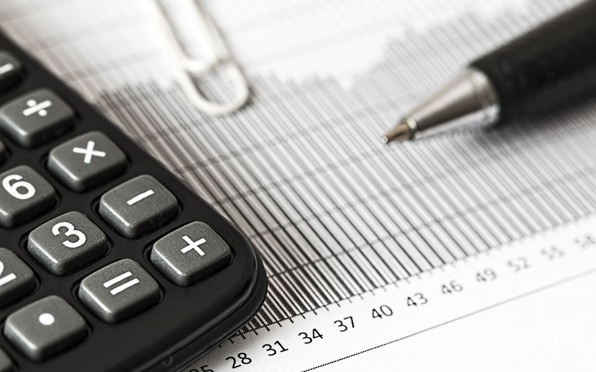 A calculator, a pen and a paper clip resting on a printed financial statement