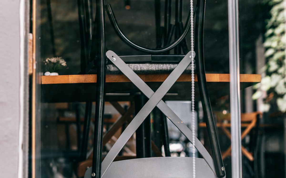 A chair turned upside down on a table, seen through the window of a closed cafe
