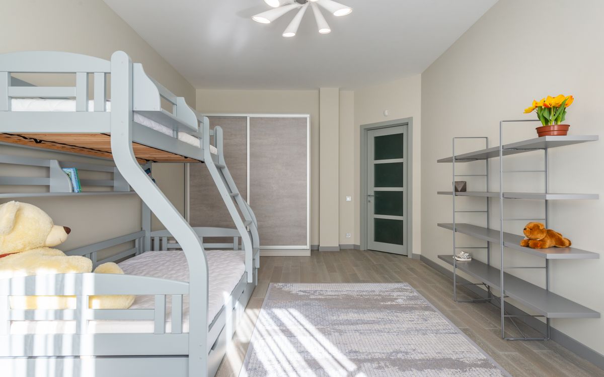 An empty children's bedroom with a bunk bed, soft toys and afternoon light