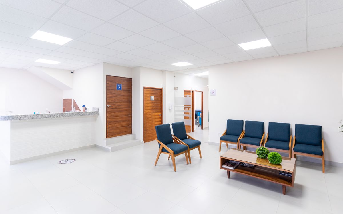An empty clinic waiting area with chairs and a reception counter