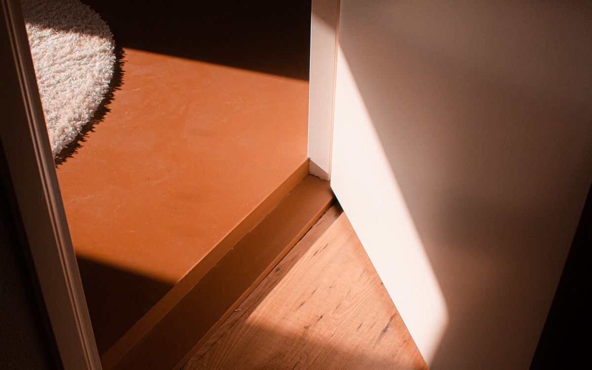 Afternoon light falling across a wooden threshold between two rooms