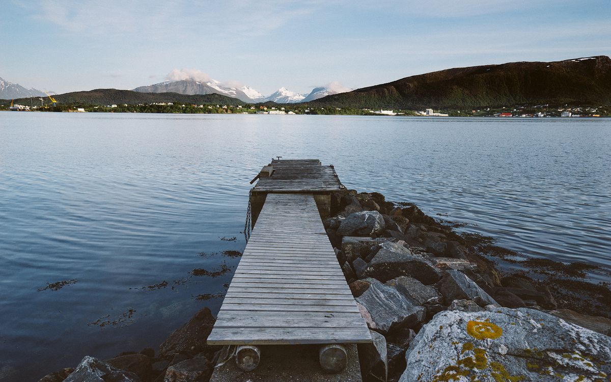 An empty wooden dock reaching into a calm lake on a clear summer day