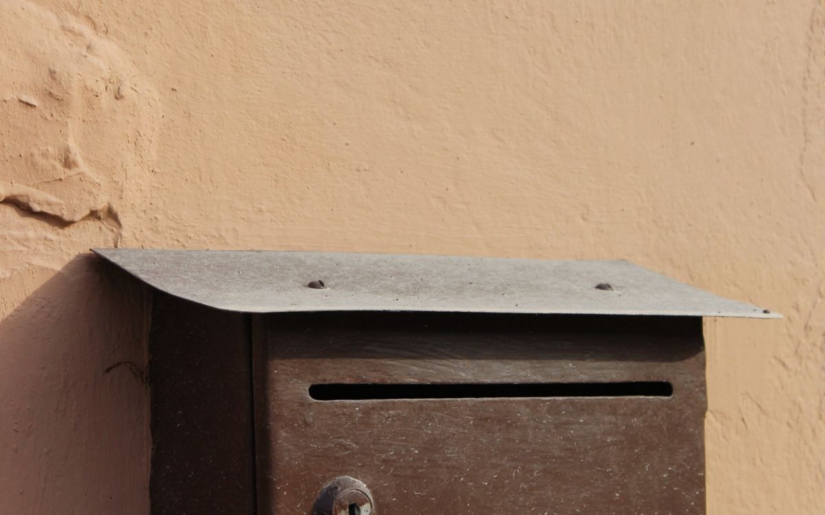 A metal mailbox mounted on a warm-toned exterior wall