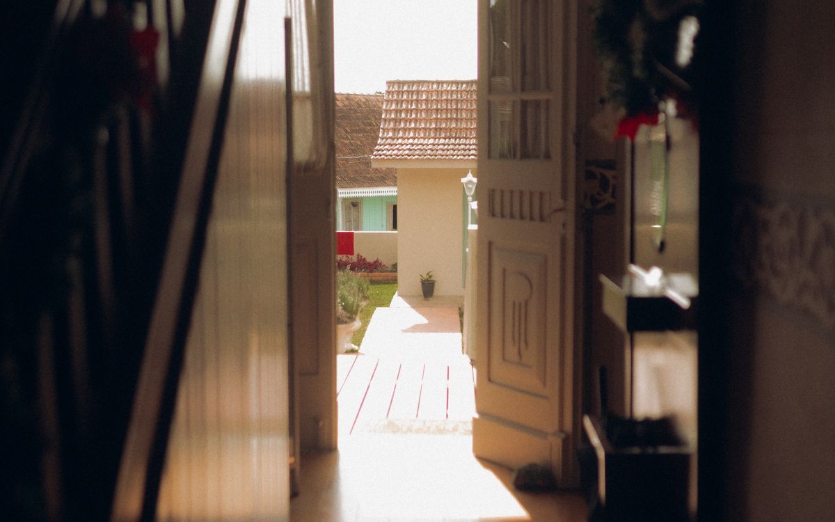 An open interior door looking out onto a sunlit garden path