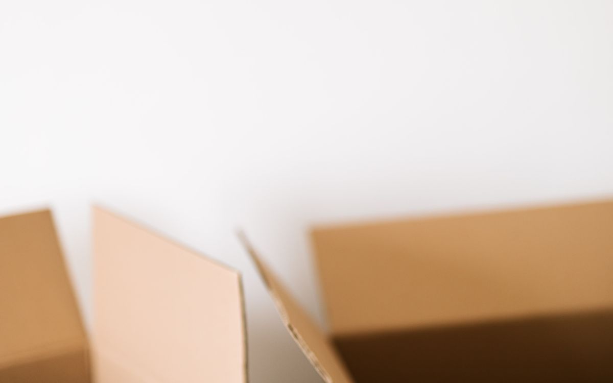 An open empty cardboard box against a plain white wall