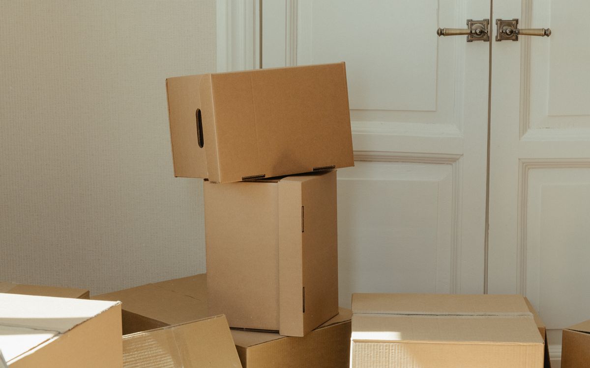 Cardboard boxes stacked beside a white door in a hallway