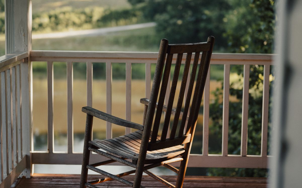 An old wooden rocking chair on the porch of a country house in late afternoon light