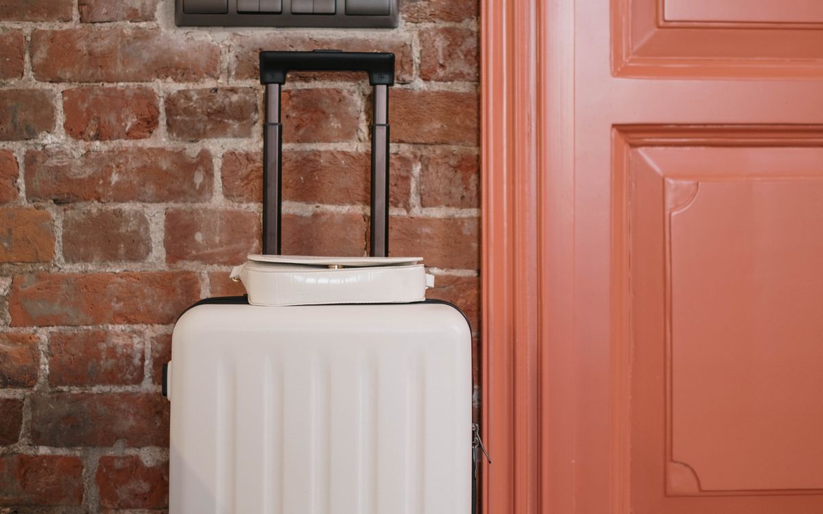 A packed suitcase and a small bag standing beside a front door