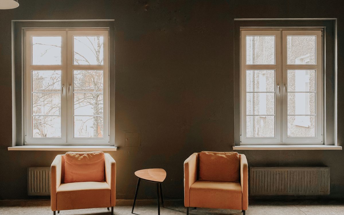 Two armchairs side by side under separate windows, with a small table between them