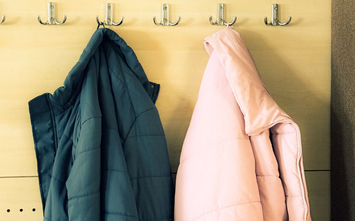 Two winter coats hanging on a row of hooks with empty hooks between them